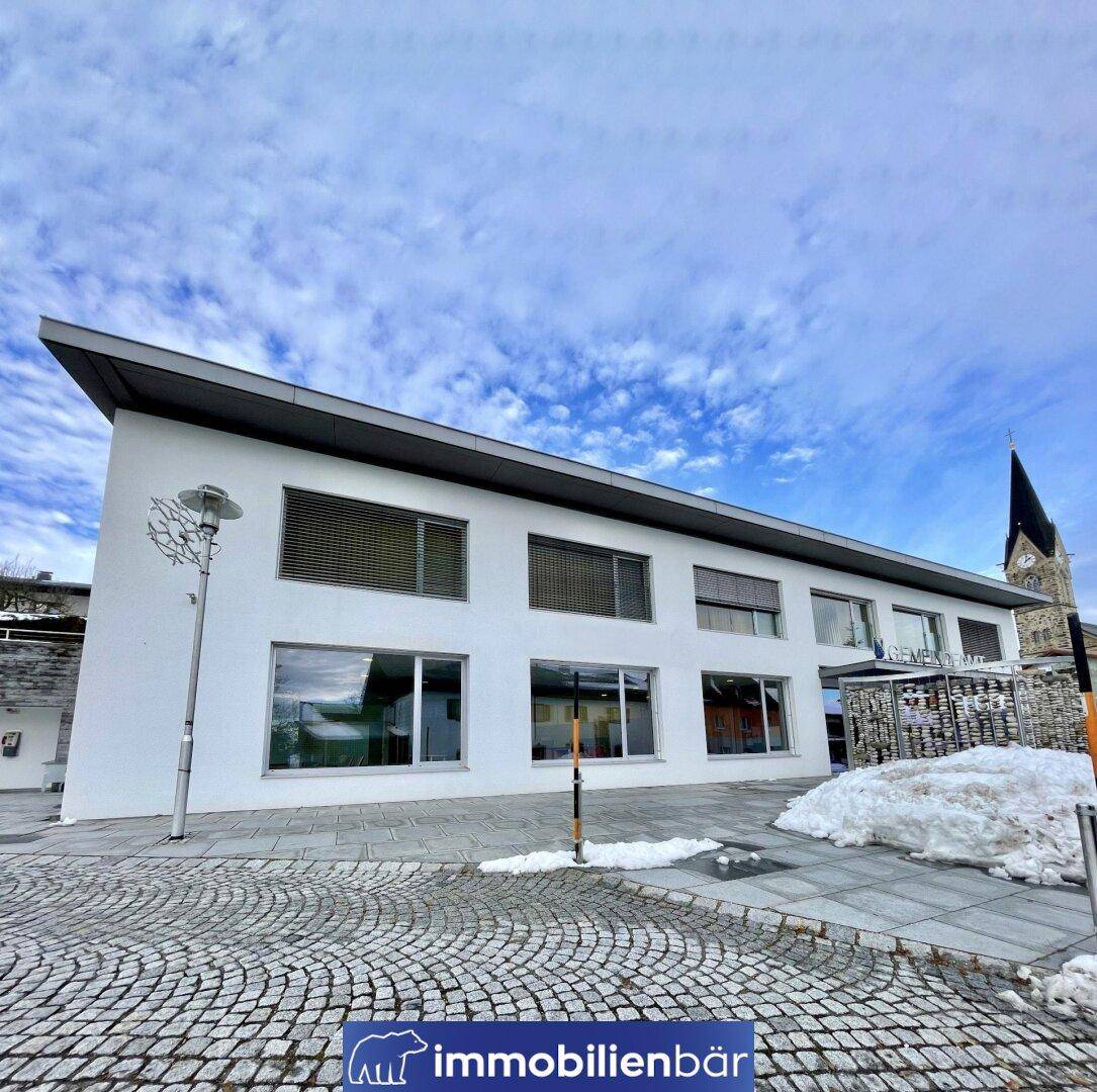 Ansicht des modernen weißen Gebäudes mit flachem Dach und großen Fenstern unter einem bewölkten Himmel.