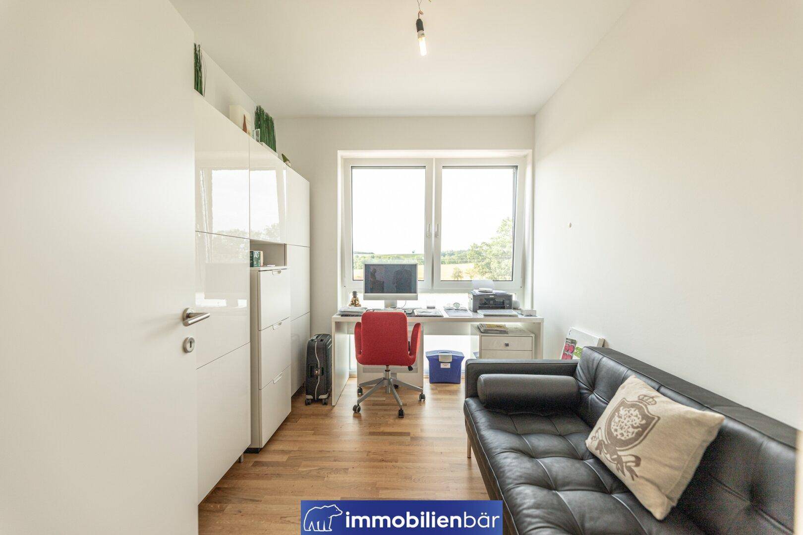 Helles Arbeitszimmer mit Schreibtisch, Bürostuhl und einem bequemen Sofa, ideal für Home-Office oder Gäste.
