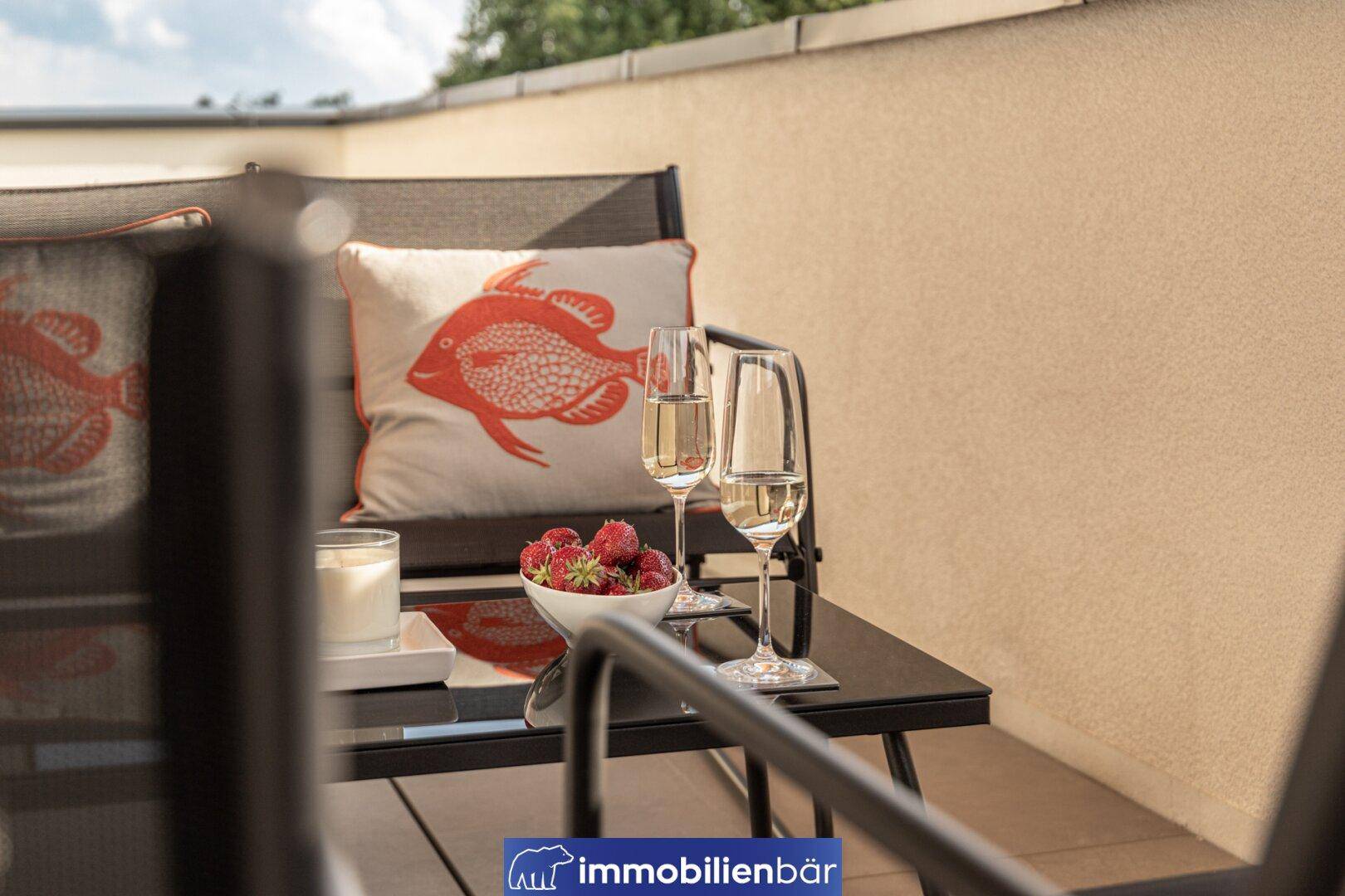 Detailansicht des gemütlichen Außenbereichs auf der Terrasse mit erfrischenden Getränken und frischen Erdbeeren.