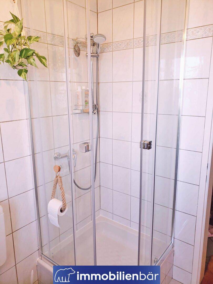 Geflieste Duschkabine mit Glaswänden in einem hellen Badezimmer.