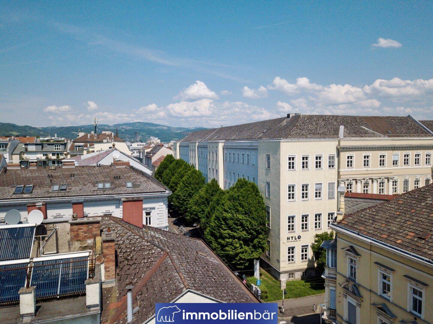 Panoramablick über die Stadt mit historischen Gebäuden und grünen Baumreihen.