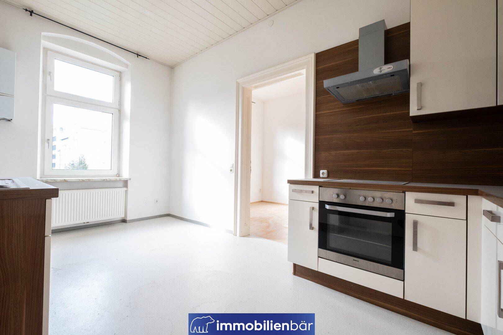 Helle Küche mit einfacher Einbauzeile, Holzdecke und Fenster für natürliches Licht.
