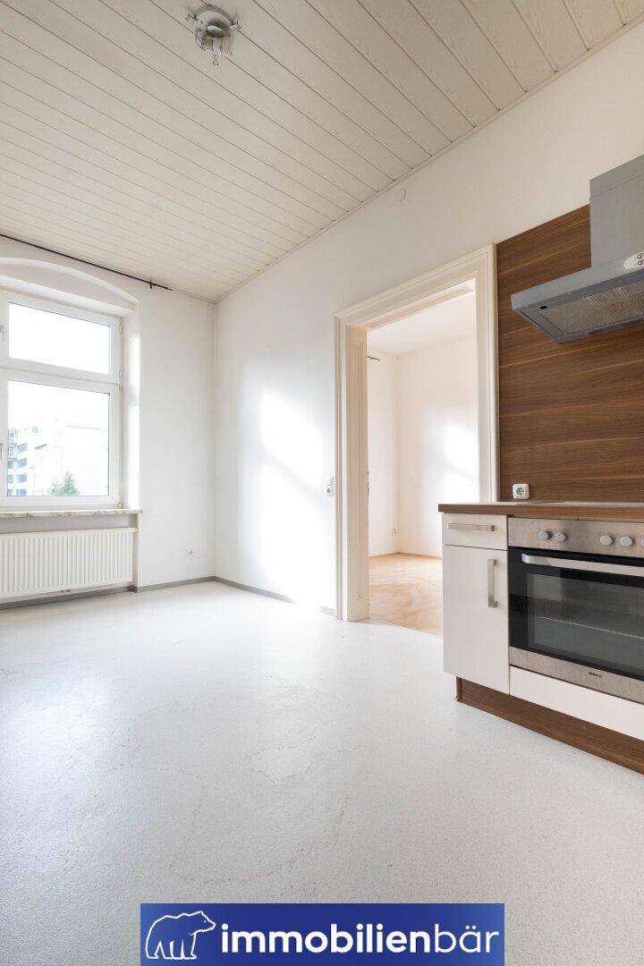Helle Küche mit einfacher Einbauzeile, Holzdecke und Fenster für natürliches Licht.
