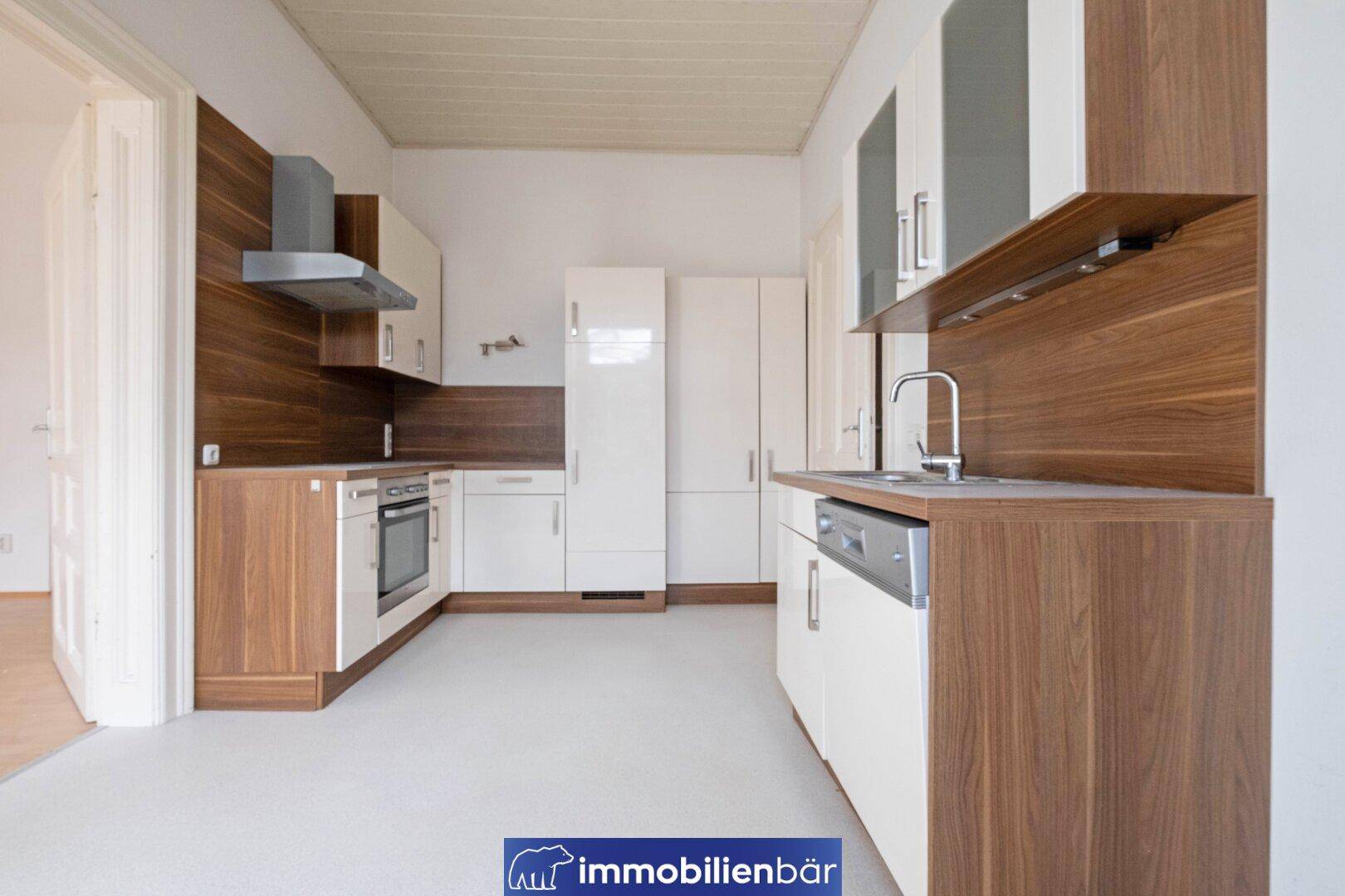 Moderne Küche mit weißen Schränken, Holzakzenten, Spülmaschine und integriertem Kühlschrank.