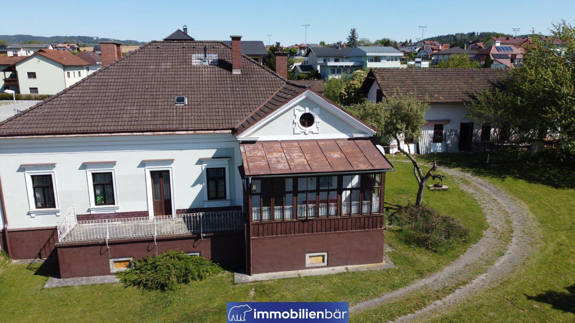 Historisches Wohnhaus mit Satteldach und verglastem Anbau in ländlicher Umgebung.