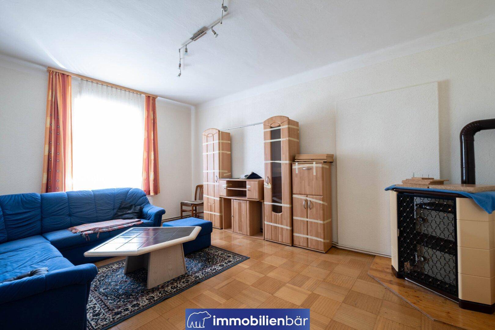 Wohnzimmer mit blauer Couch, Holzboden und traditionellen Holzmöbeln.