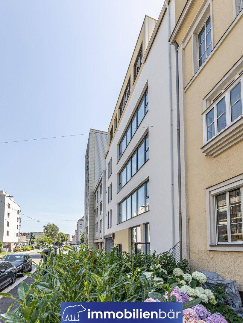 Seitenansicht des modernen Gebäudes mit großen Fenstern und Blick auf die Straße mit parkenden Autos.