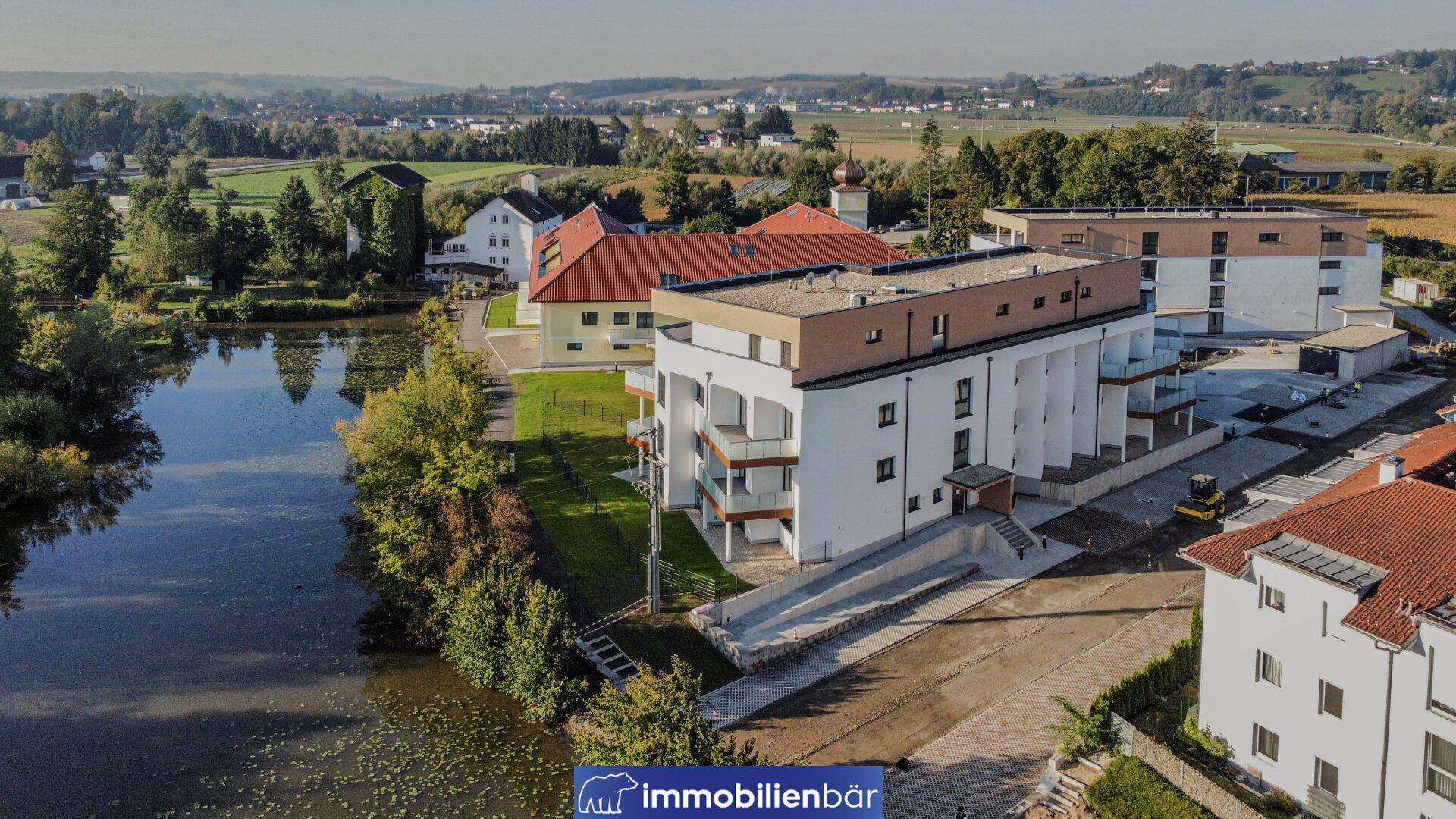 Modernes Wohngebäude am Teich mit Balkonen und Blick auf die umliegende Natur.
