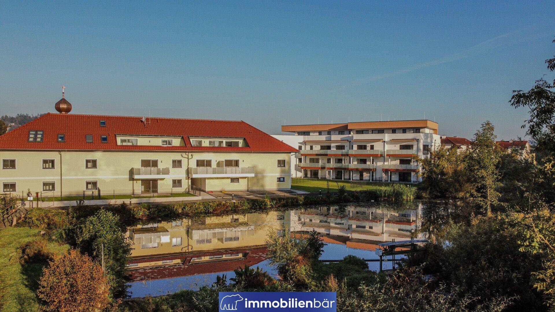 Wohngebäude am Wasser mit moderner Architektur und traditionellem Bau im Hintergrund.