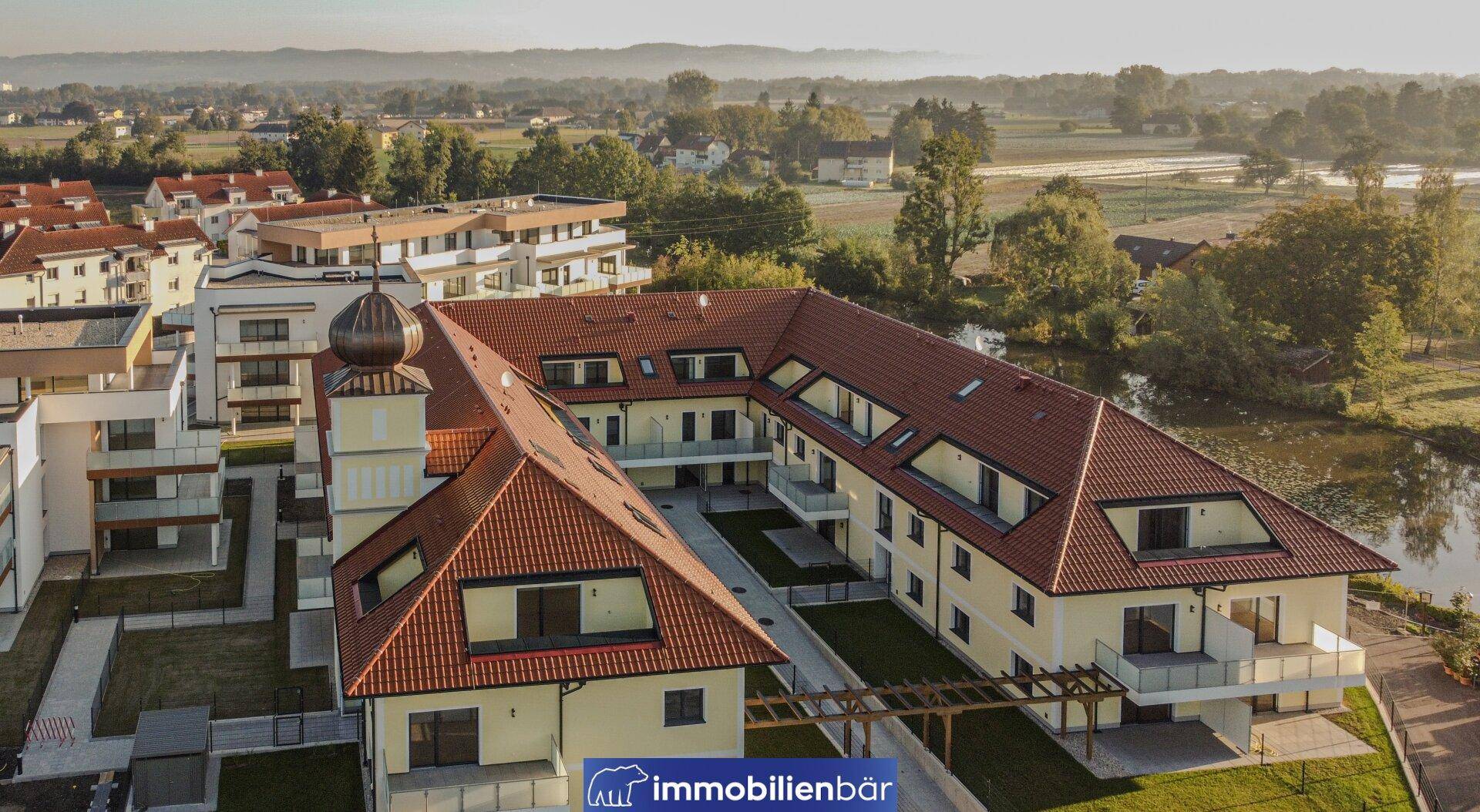 Luftaufnahme eines Wohnkomplexes mit traditionellem Gebäude, modernen Bauten und Teich.