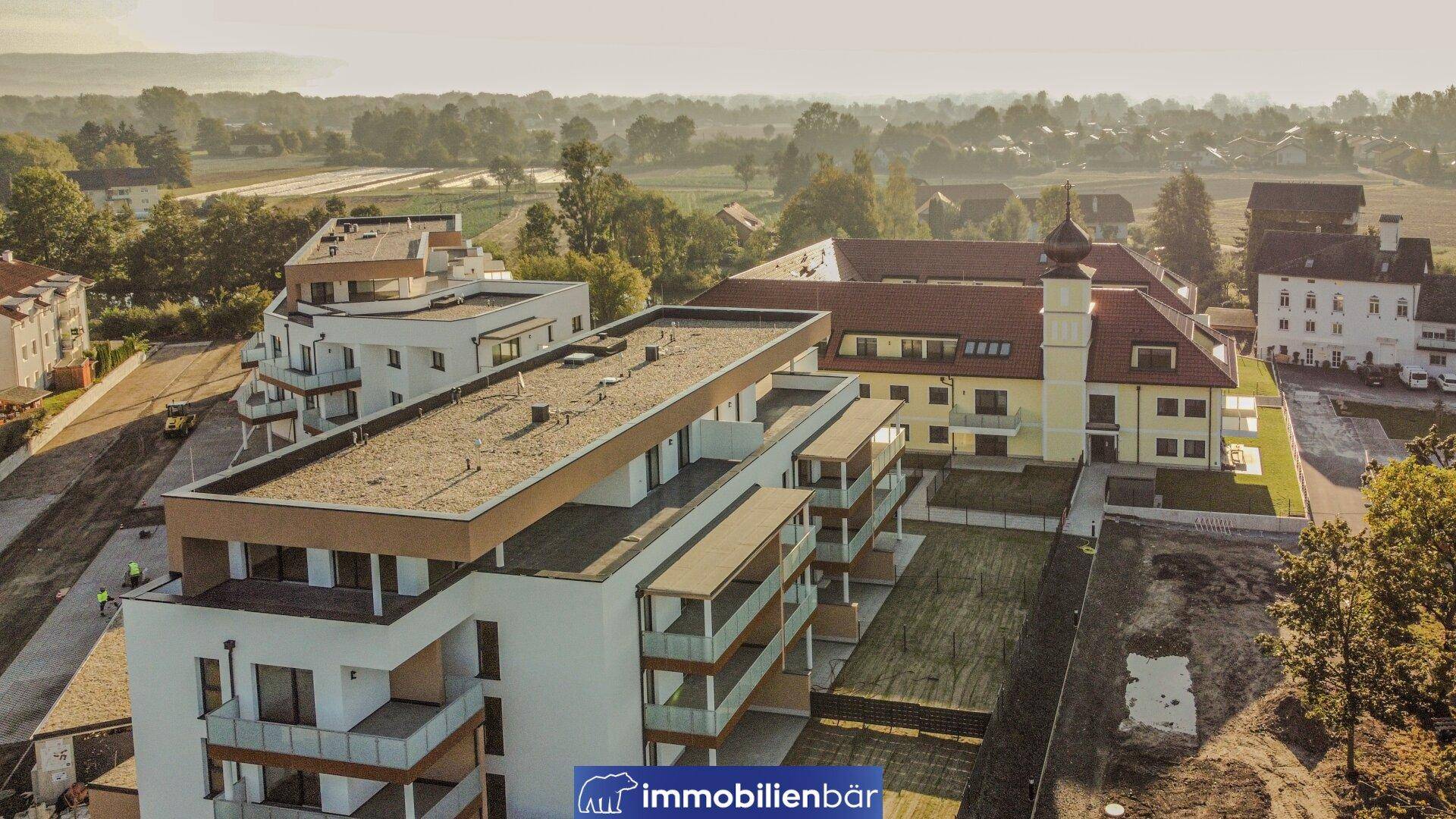 Luftaufnahme eines neuen Wohnkomplexes mit Flachdachgebäuden und einem traditionellen Bau.