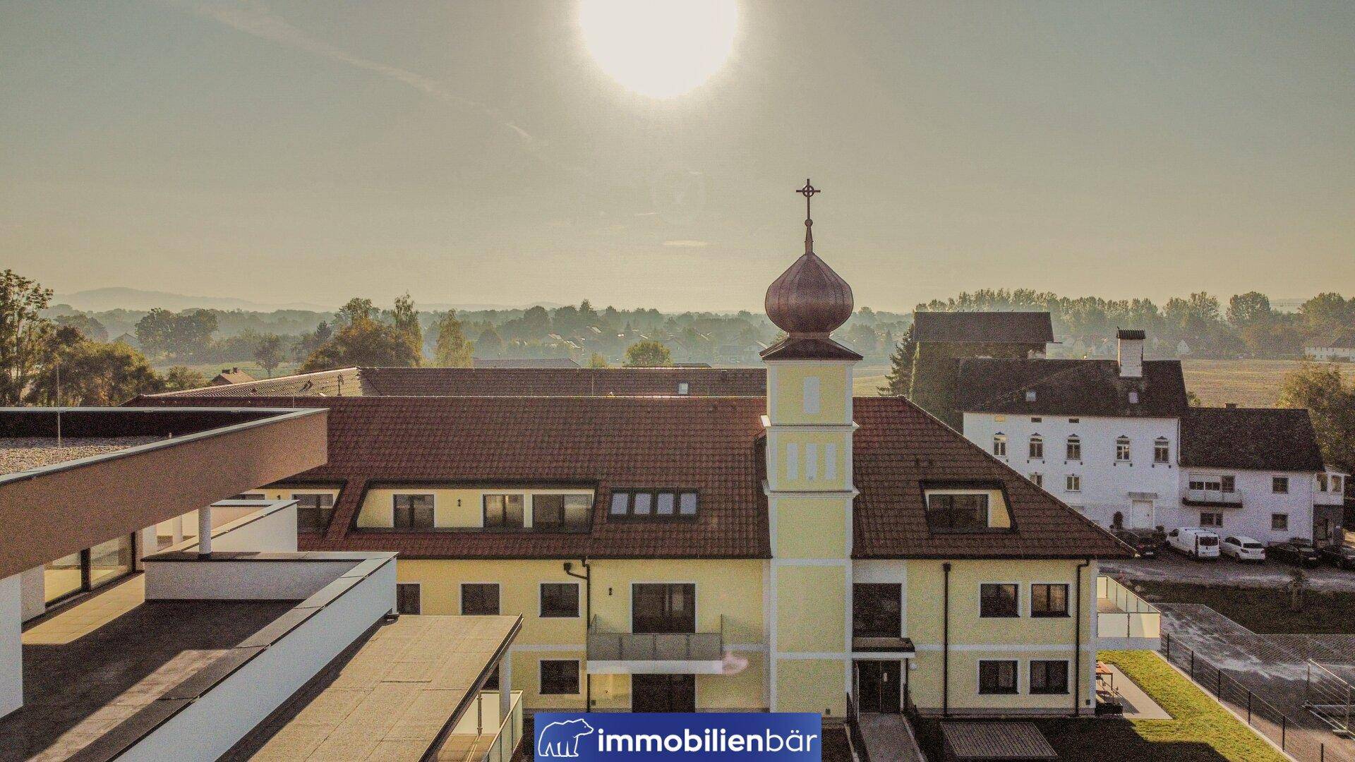 Sonnenbeschienene Ansicht eines Wohnkomplexes mit traditionellem Gebäude und modernen Bauten.