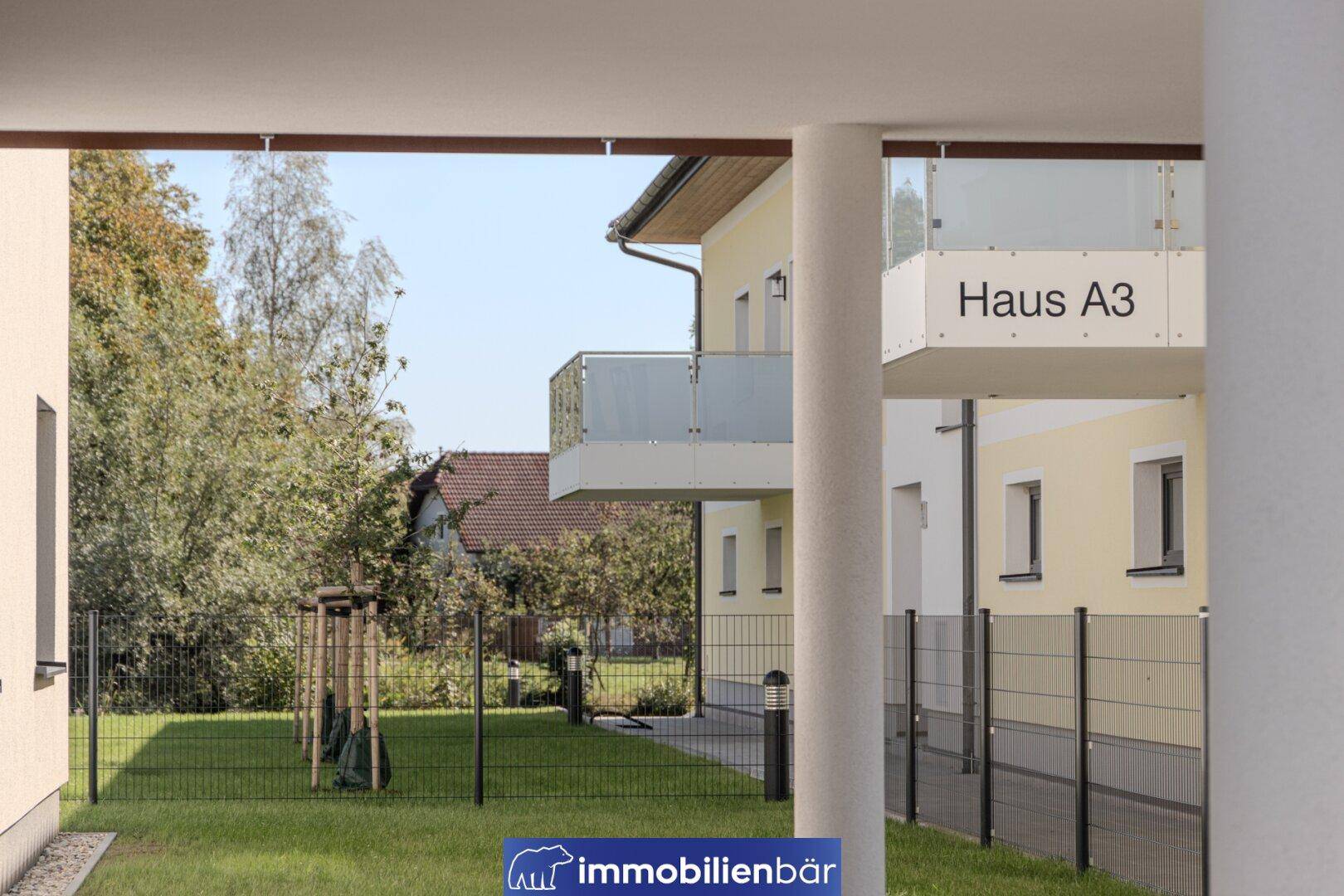 Gepflegter Gartenbereich mit Rasen und Blick auf die moderne Wohnanlage.