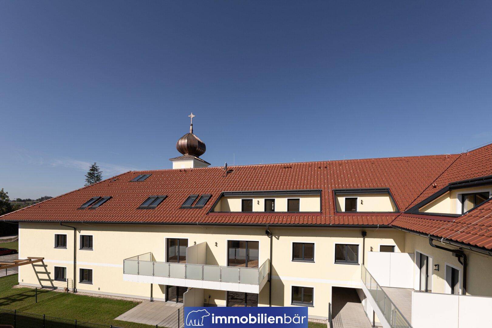 Ansicht eines traditionellen Wohngebäudes mit rotem Ziegeldach und Dachfenstern.