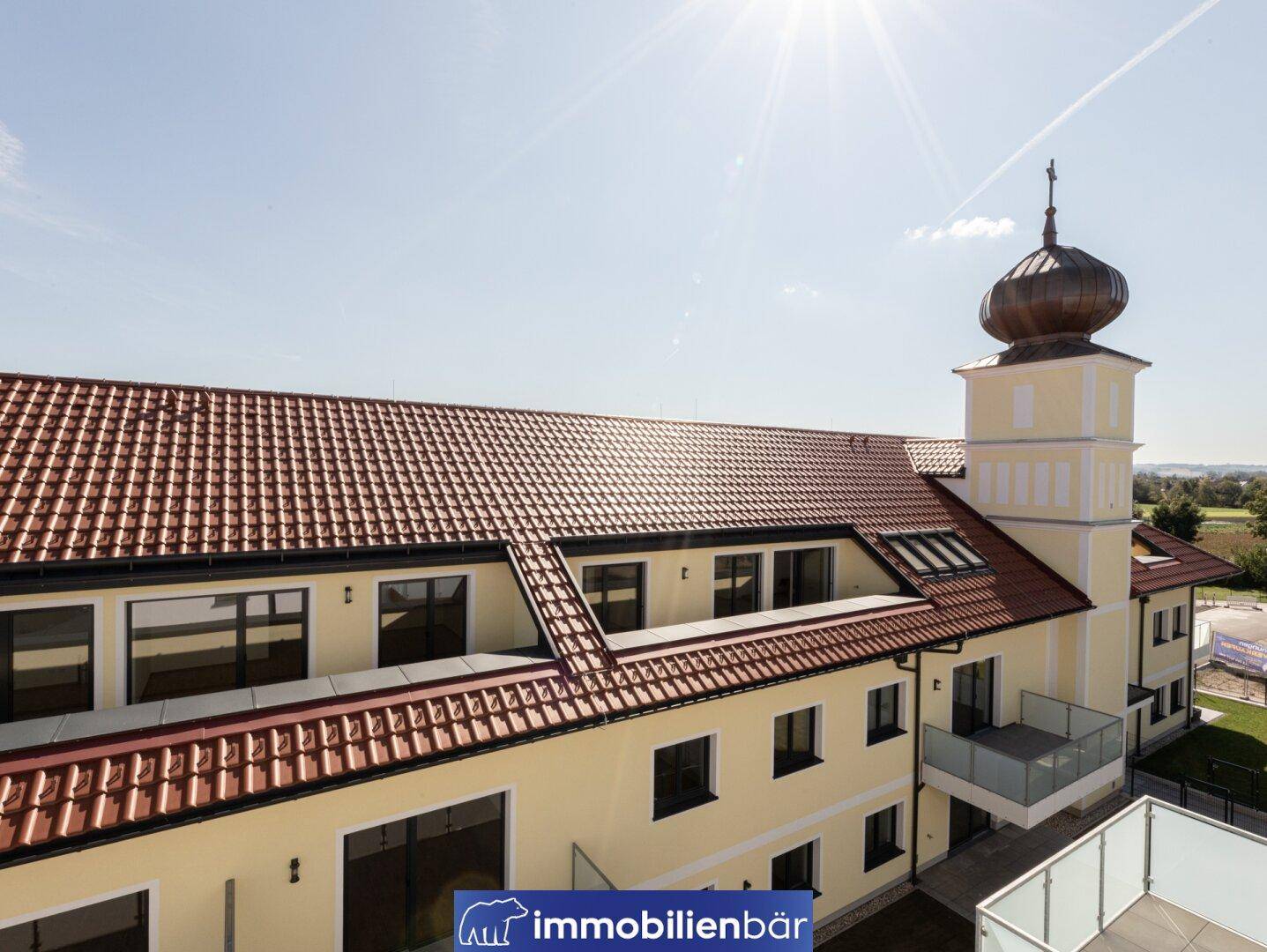 Ansicht eines traditionellen Wohngebäudes mit rotem Ziegeldach und Dachfenstern.