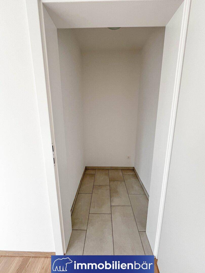 Praktischer Abstellraum mit Fliesenboden und weißen Wänden für zusätzlichen Stauraum.