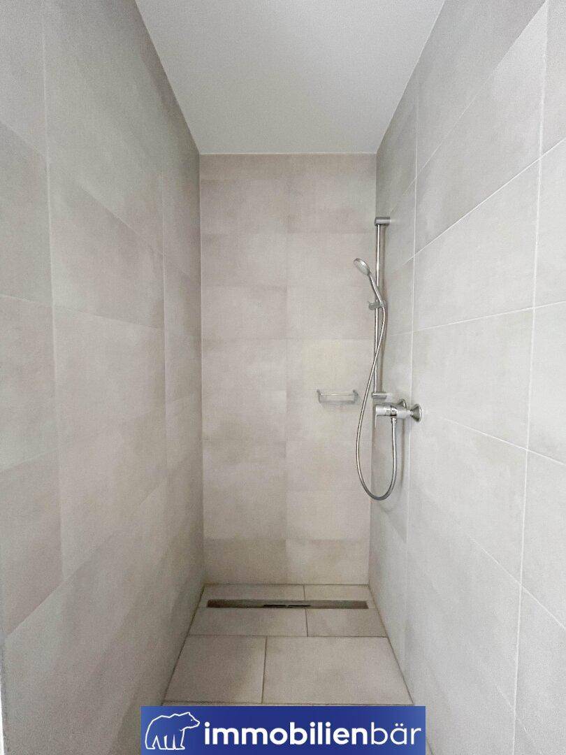 Geräumige, ebenerdige Dusche mit modernen Fliesen und minimalistischem Design.