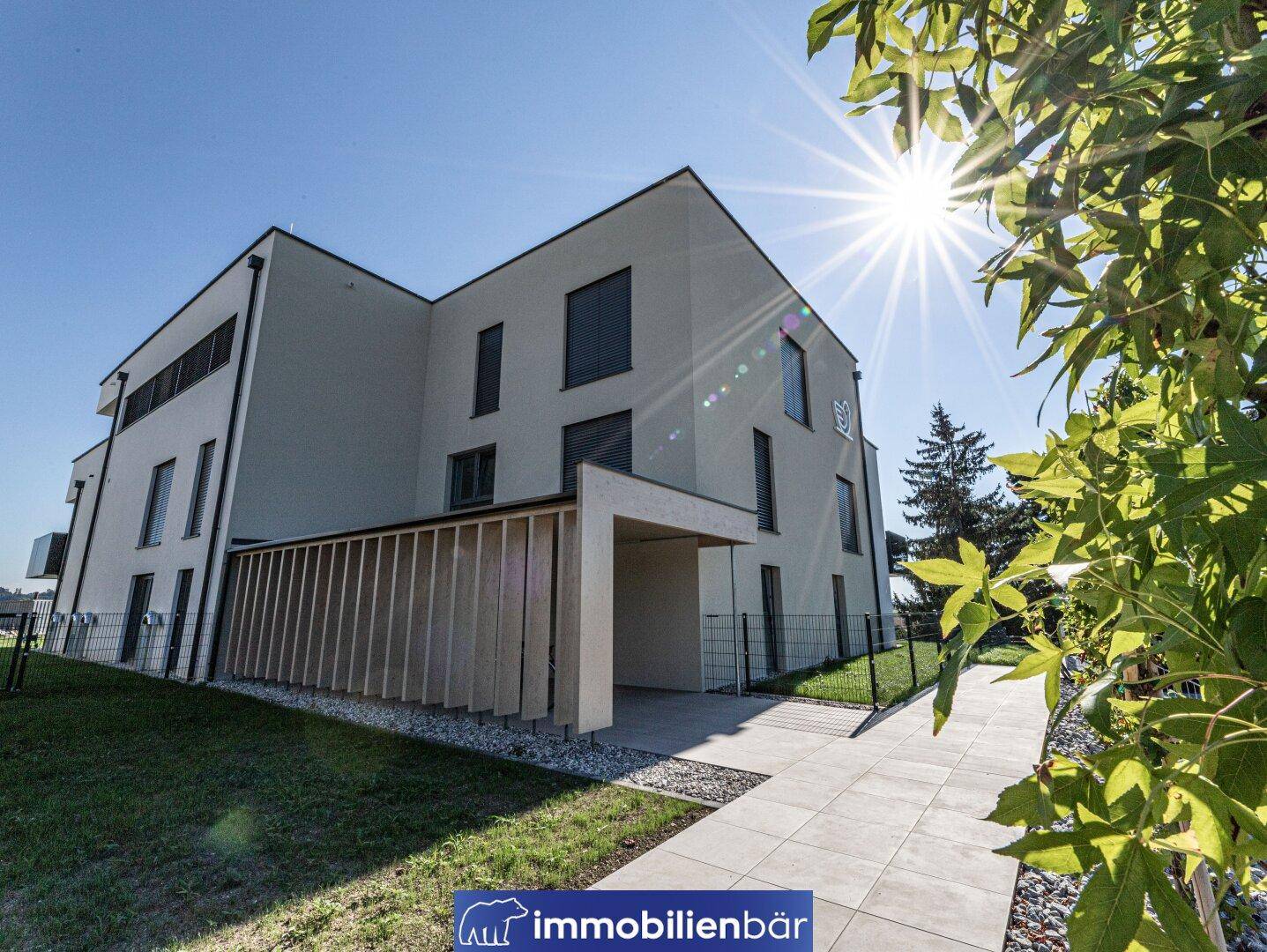 Moderne Architektur des Neubaus mit klaren Linien, großzügigen Fensterflächen und einem überdachten Carport.