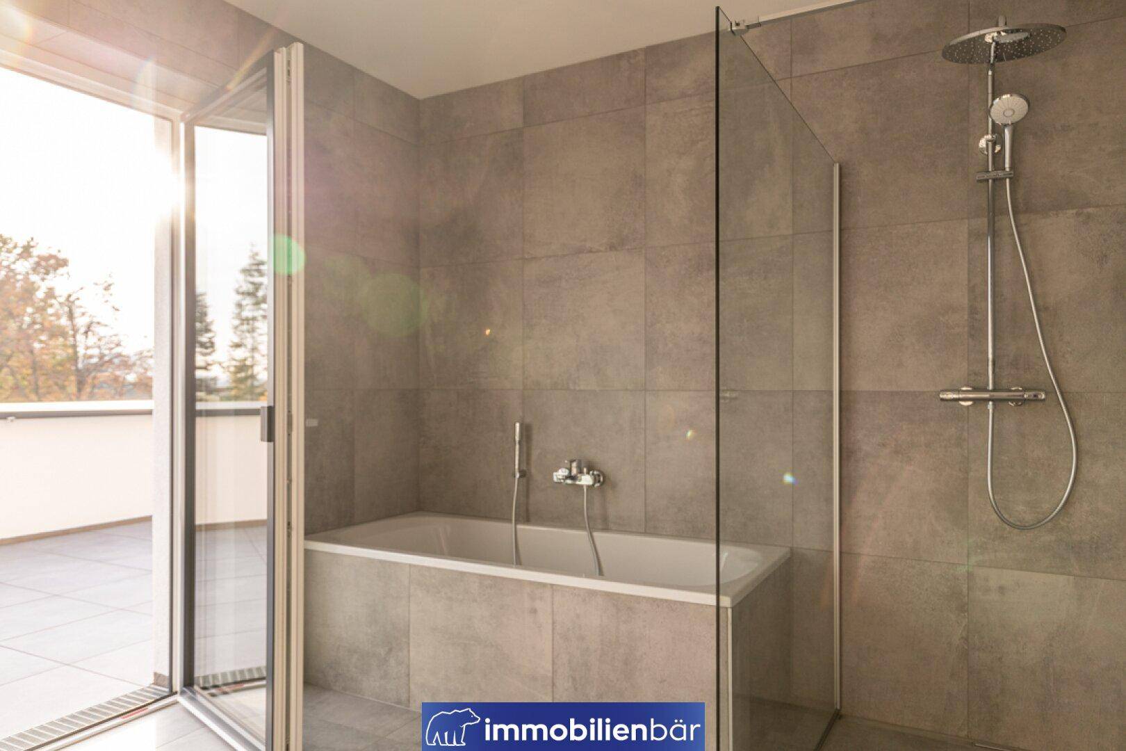 Modernes Badezimmer mit Badewanne, Duschabtrennung und großen Fenstertüren zur Terrasse.