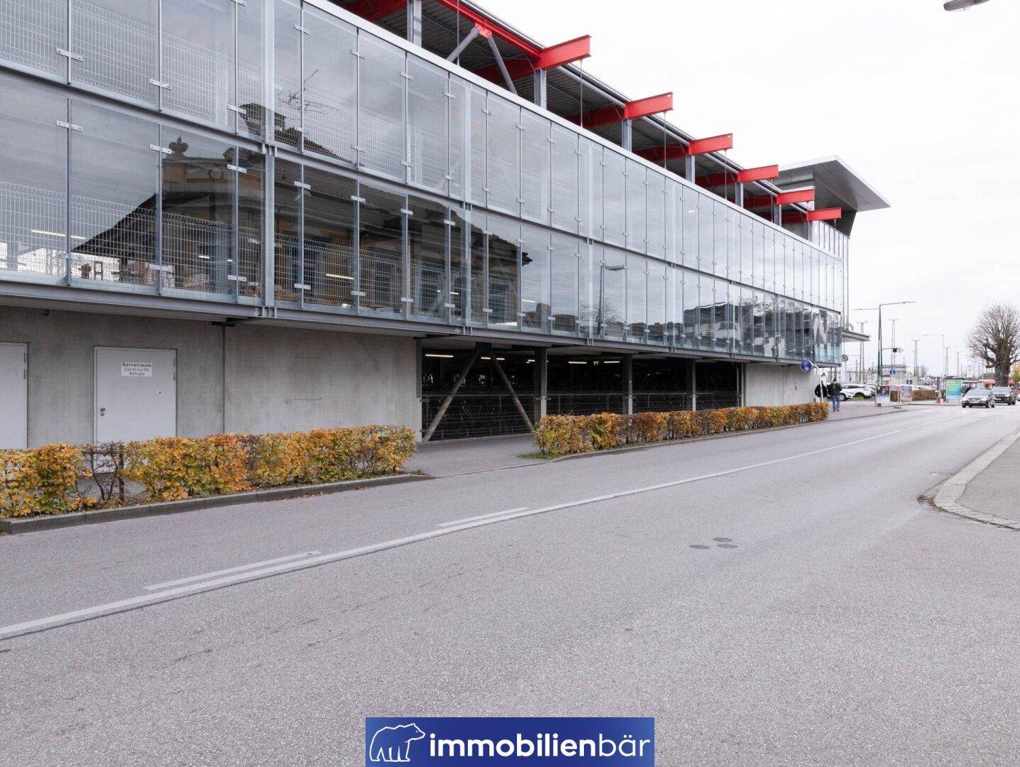 Moderne Außenansicht eines Gebäudes mit Glasfassade und einer Straße im Vordergrund.