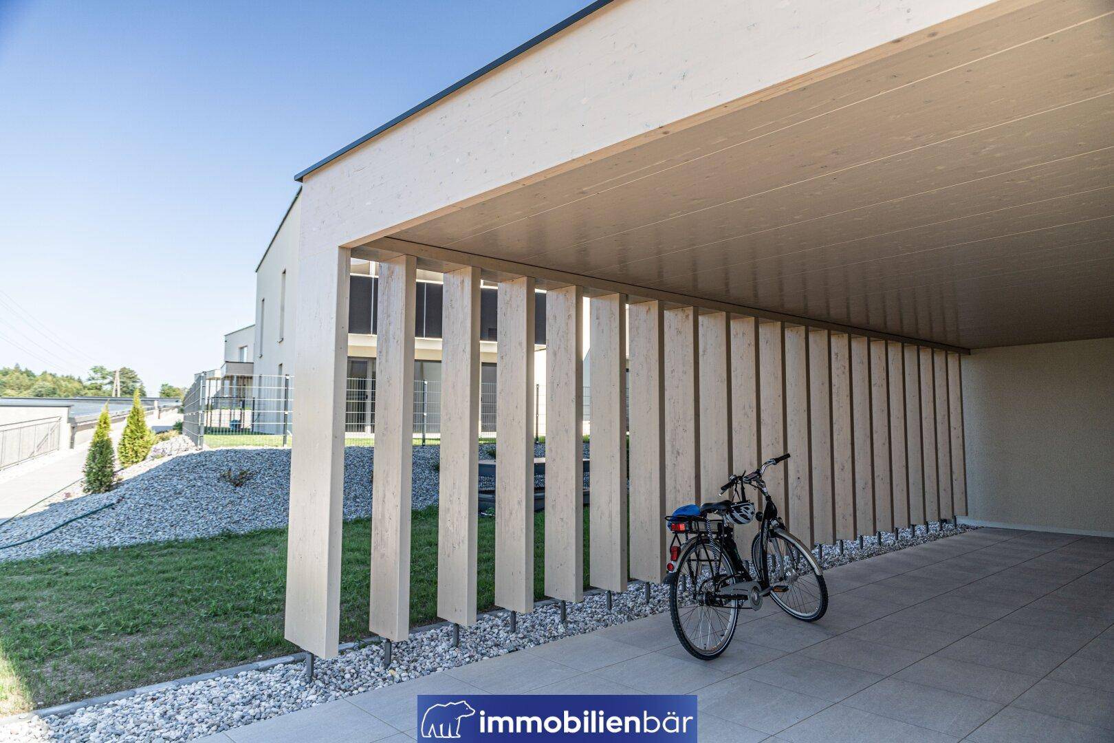 Detailansicht eines modernen Carports mit Holzlamellen und Fahrradstellplatz.