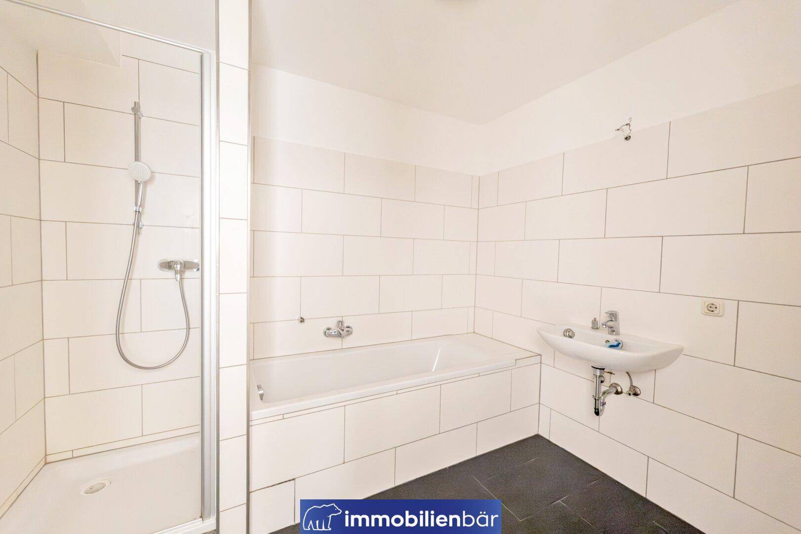 Helles Badezimmer mit Badewanne, Dusche, Waschbecken und weißen Wandfliesen.