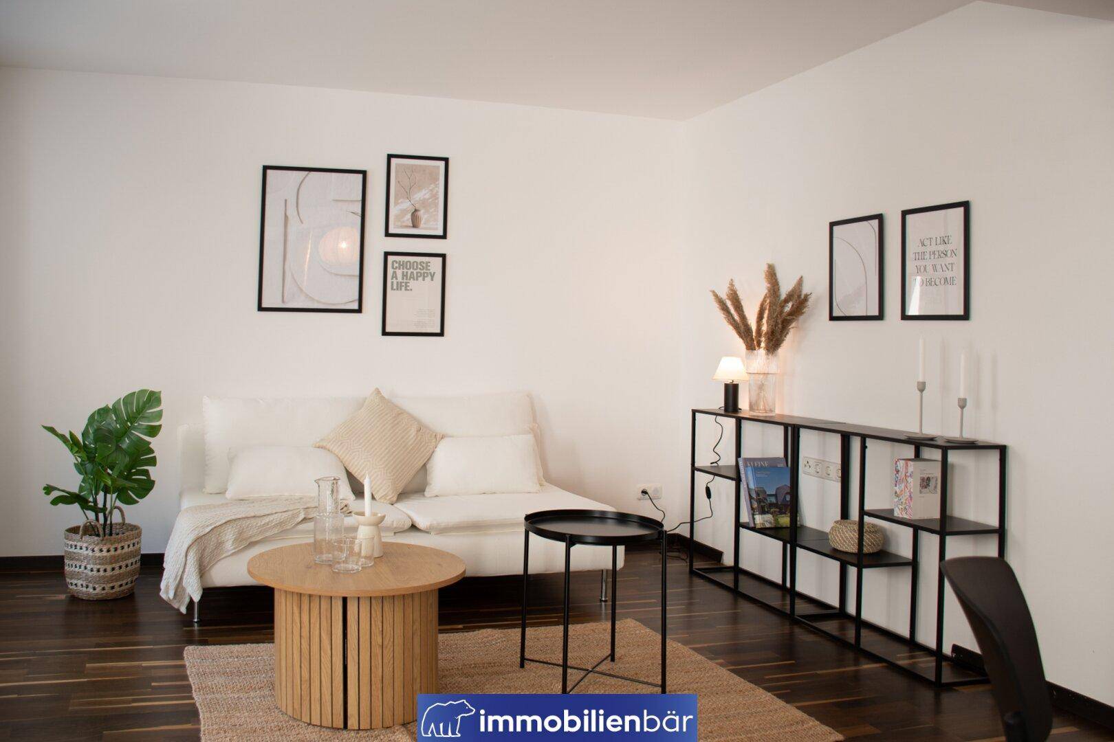 Modern eingerichtetes Wohnzimmer mit weißem Sofa, dunklem Holzboden und minimalistischer Dekoration.