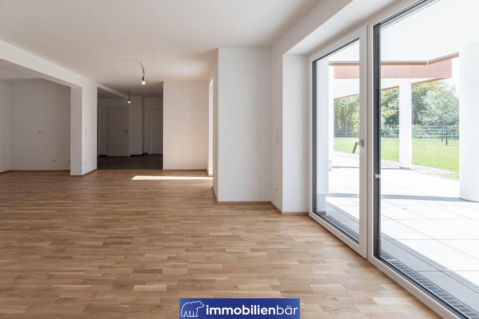 Geräumiger, heller Wohnbereich mit Parkettboden und großen Schiebetüren zur Außenterrasse.