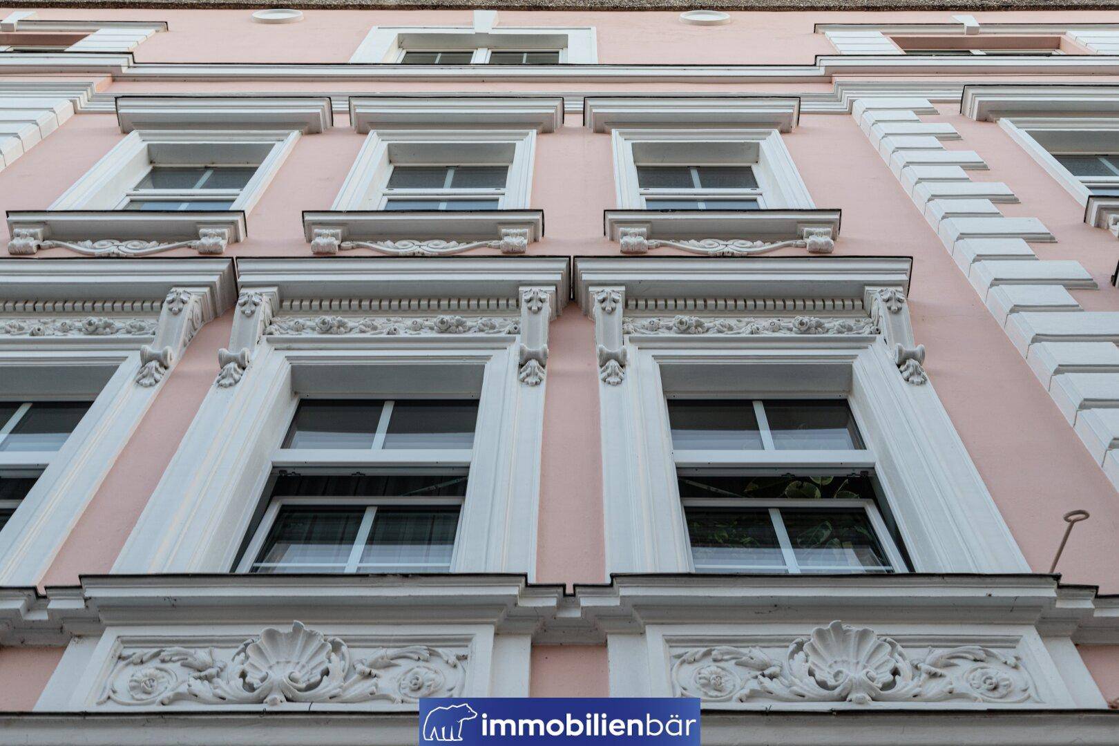 Detailaufnahme der rosa Fassade mit kunstvollen Stuckverzierungen und Fenstern.