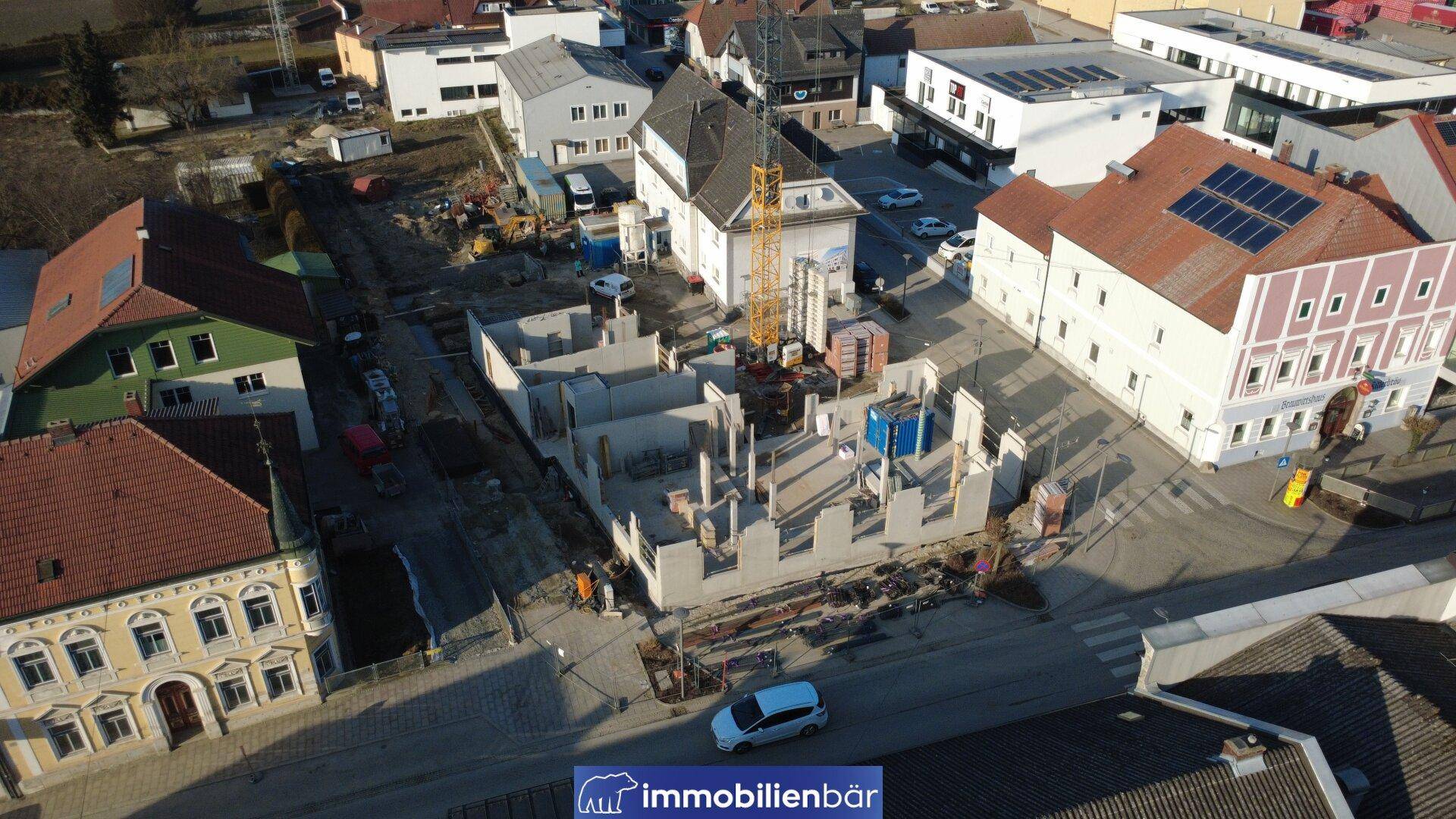 Luftaufnahme einer Baustelle mit bereits errichteten Fundamenten und Mauern in der Stadt.