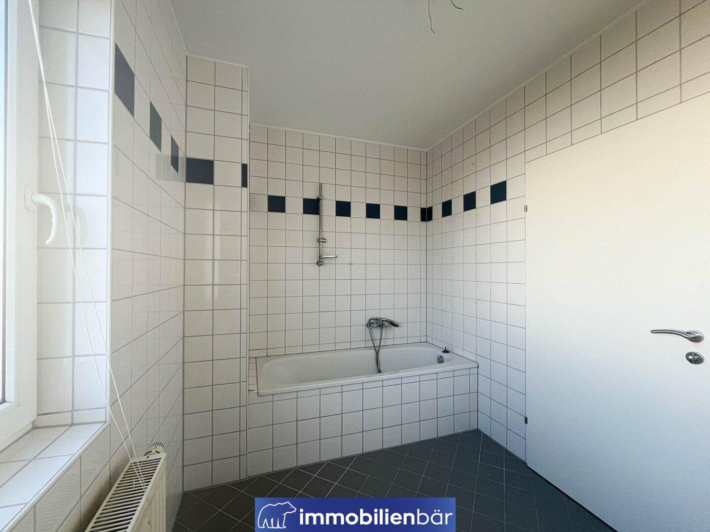 Gefliestes Badezimmer mit Badewanne und Duscharmatur, bereit für die Installation eines Waschbeckens.
