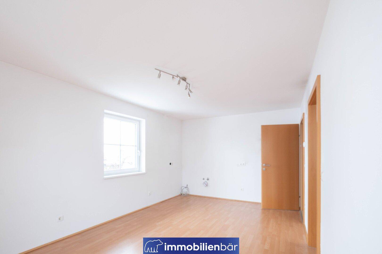 Geräumiges Zimmer mit Laminatboden und Anschlussmöglichkeiten für eine Küche oder Waschmaschine.