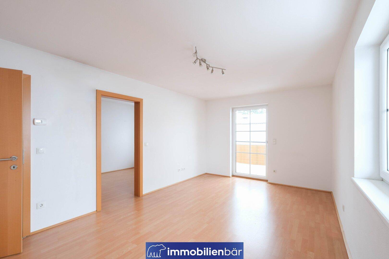 Helles Zimmer mit Laminatboden und Zugang zu einem Außenbereich, ideal für individuelle Gestaltung.