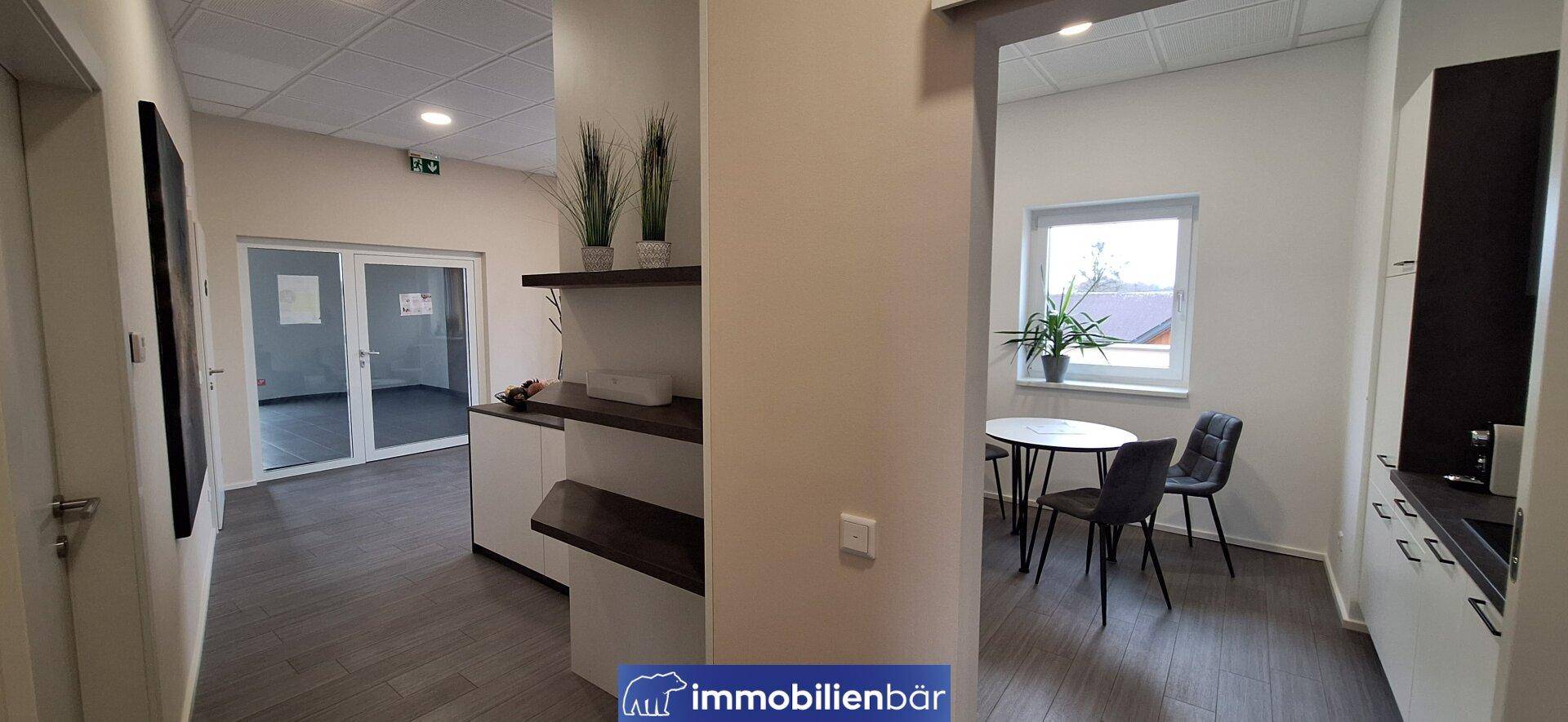 Moderner Flur mit dunklem Laminatboden, praktischen Regalen und Blick in einen hellen Essbereich.