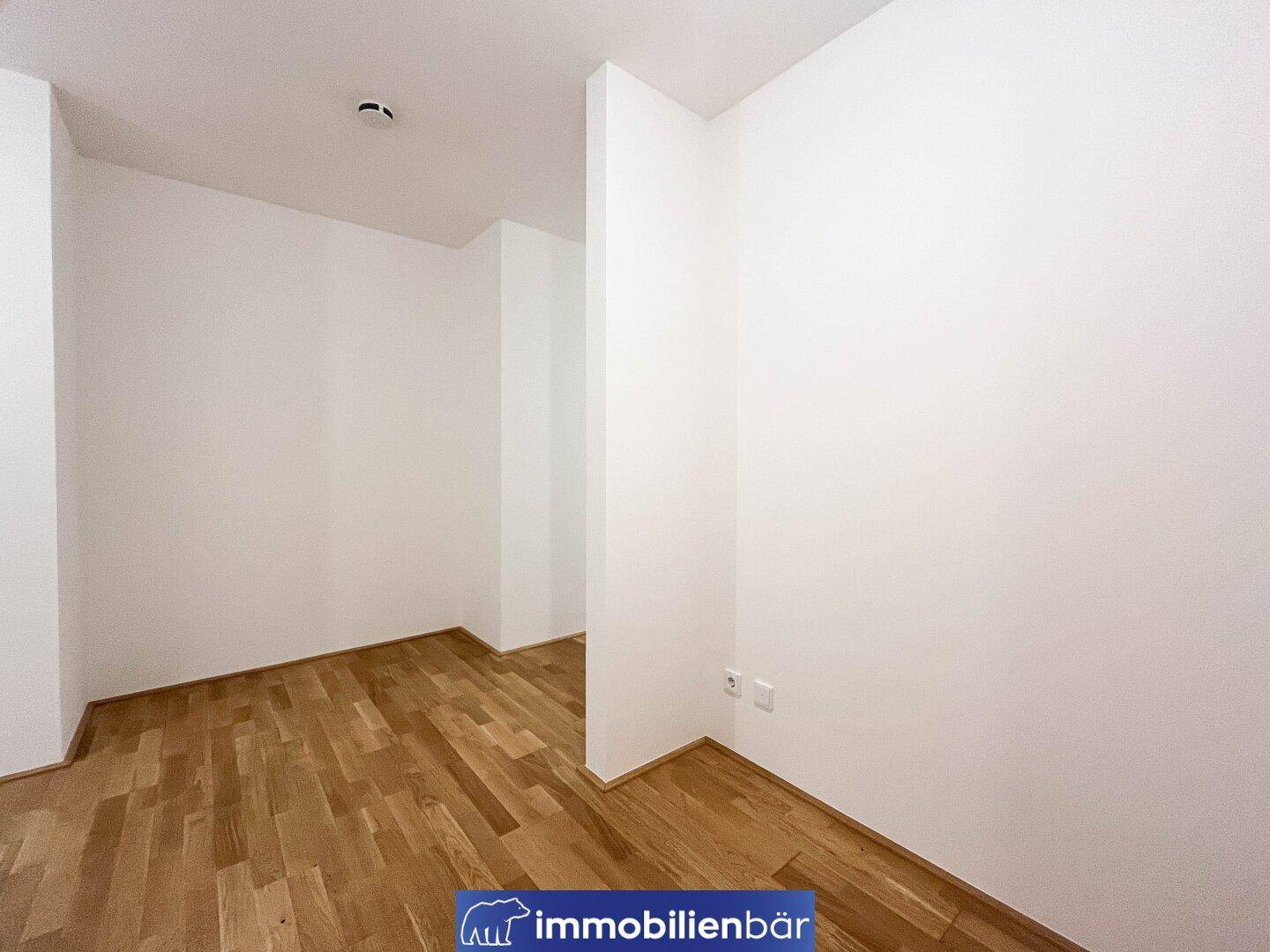 Kleiner, heller Raum mit Holzboden und weißen Wänden, vielseitig nutzbar.