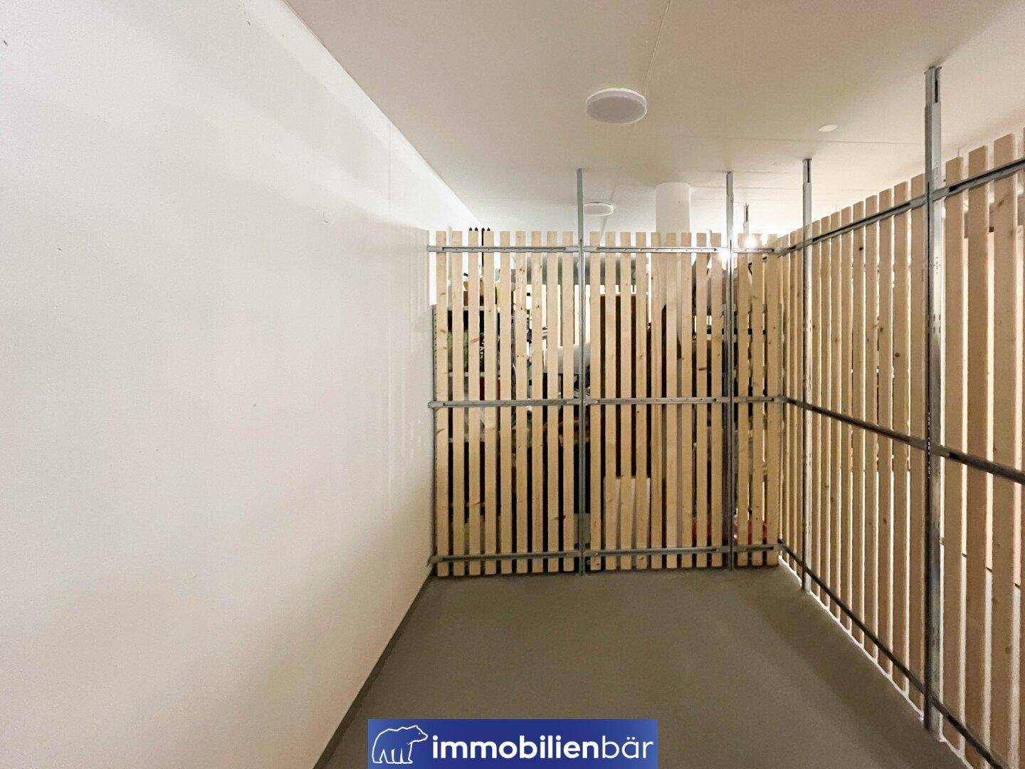 Kellerabteil mit Holzlattenwänden und Betonboden, ideal für zusätzlichen Stauraum.