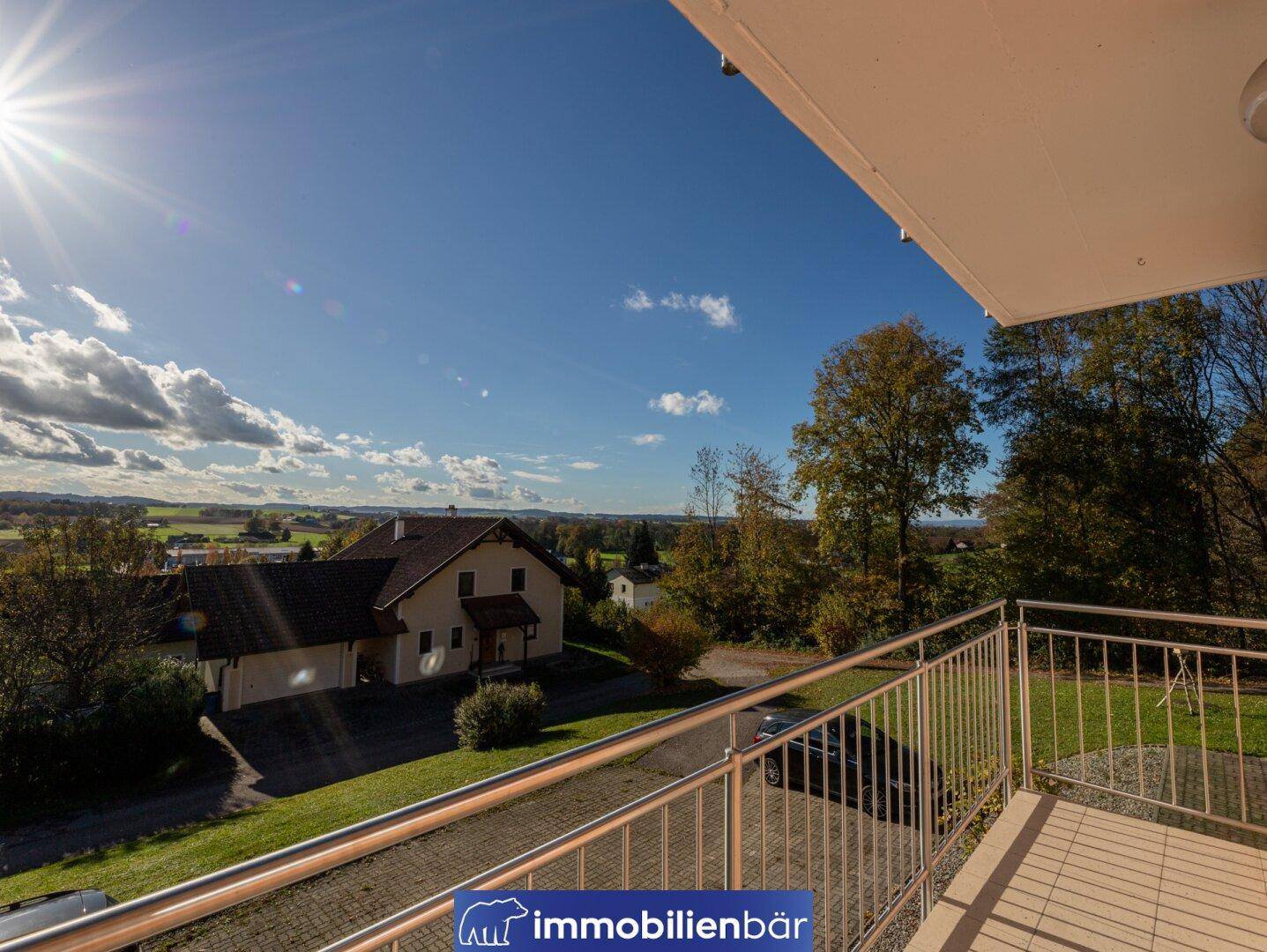 Sonniger Balkon mit weitem Blick über die ländliche Umgebung und grüne Hügel.