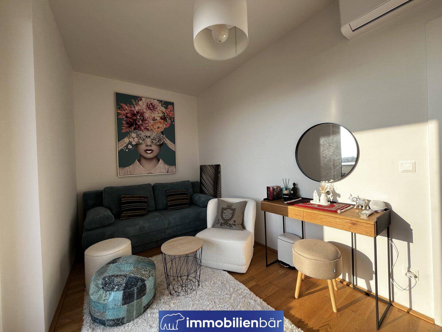 Helles Wohnzimmer mit modernem Sofa, Schminktisch und dekorativer Kunst an der Wand.