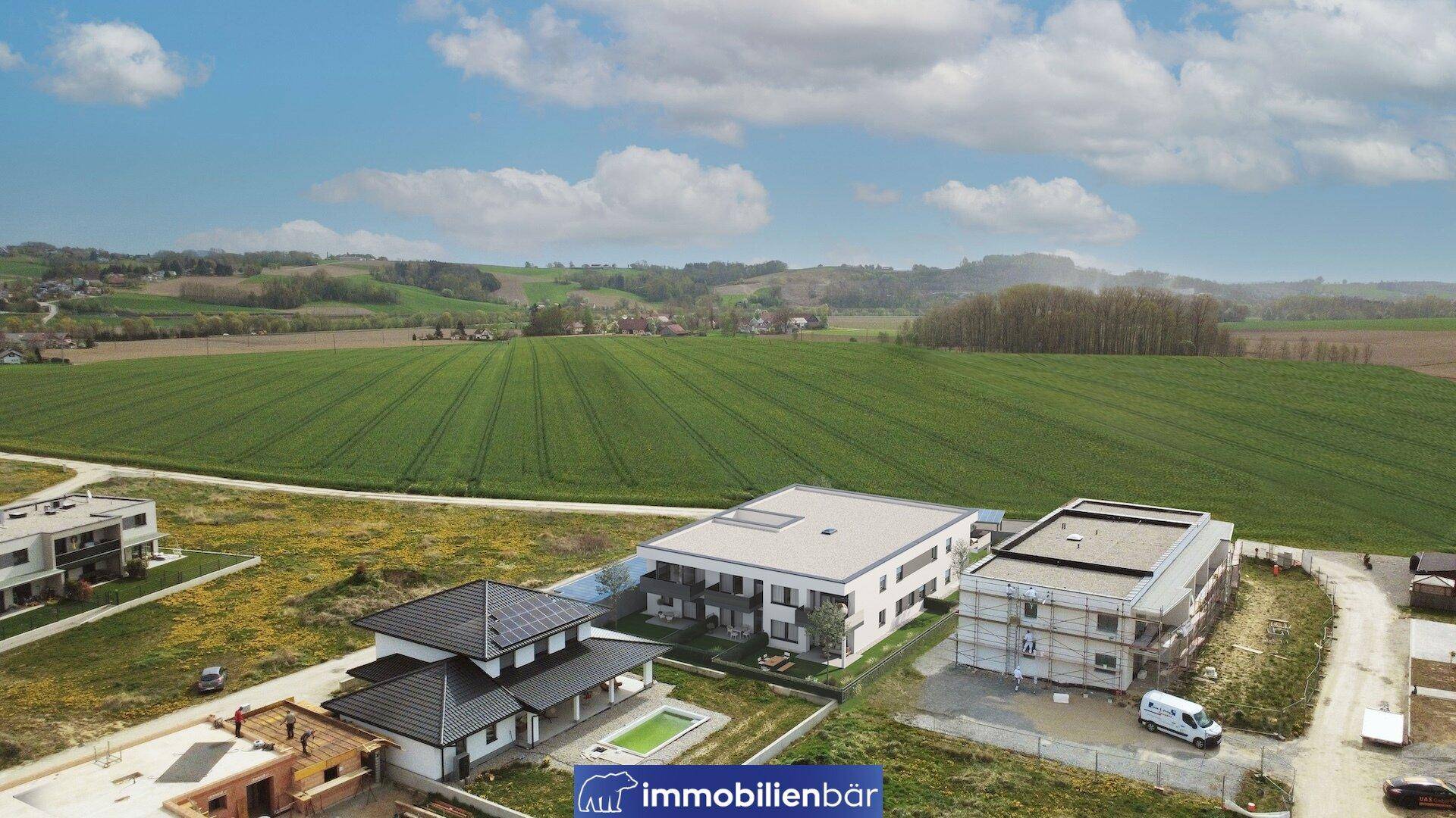 Luftaufnahme einer modernen Wohnanlage im Bau, umgeben von weiten Feldern und ländlicher Idylle.