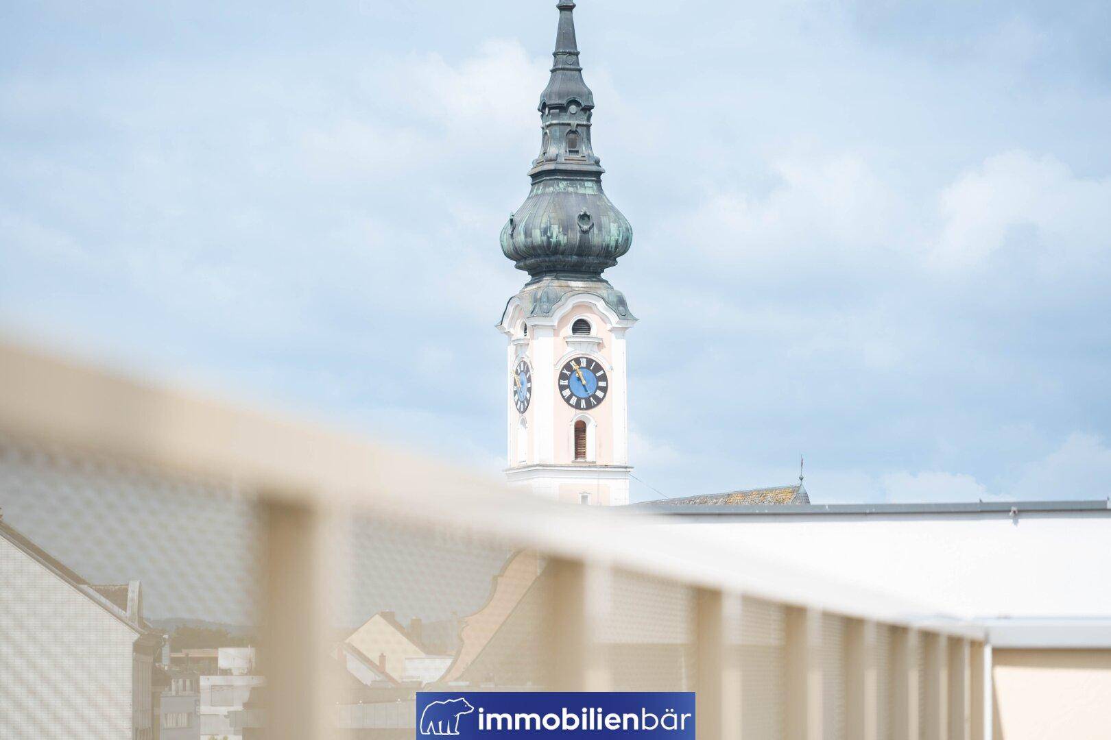 Nahaufnahme eines historischen Kirchturms mit Uhr, sichtbar von der Immobilie aus unter bewölktem Himmel.
