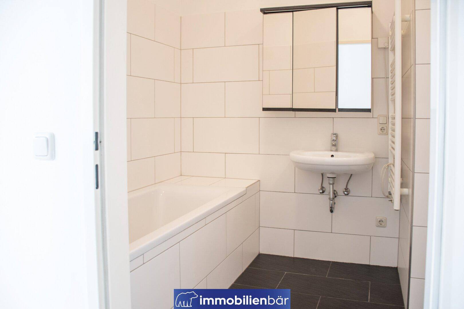 Badezimmer mit Badewanne, Waschbecken und Spiegelschrank, in schlichtem, funktionalem Design.