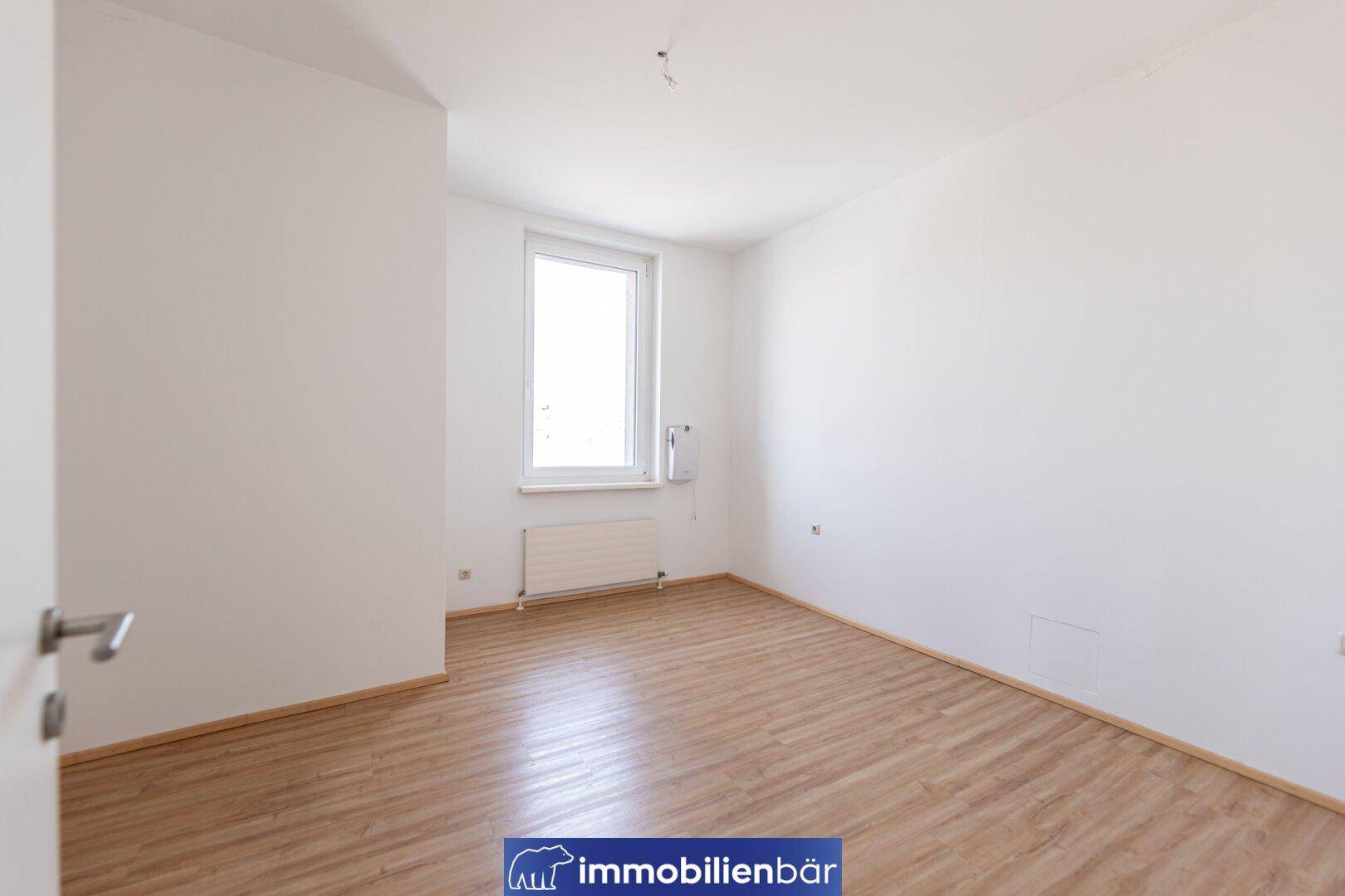 Geräumiges Zimmer mit Laminatboden und weiß gestrichenen Wänden, bereit zur individuellen Gestaltung.