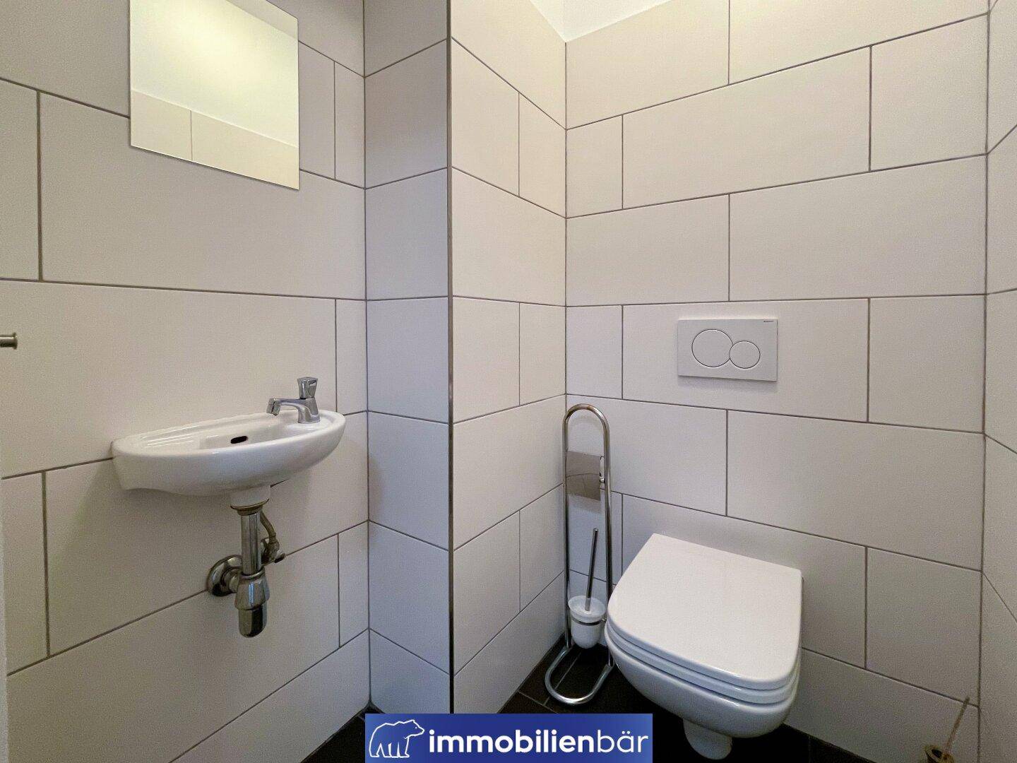 Kompaktes Gäste-WC mit modernen weißen Fliesen und wandhängender Toilette.