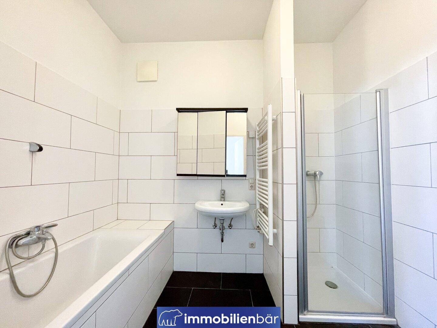 Komplettes Badezimmer mit Badewanne, Dusche, Waschbecken und Spiegelschrank, hell gefliest.