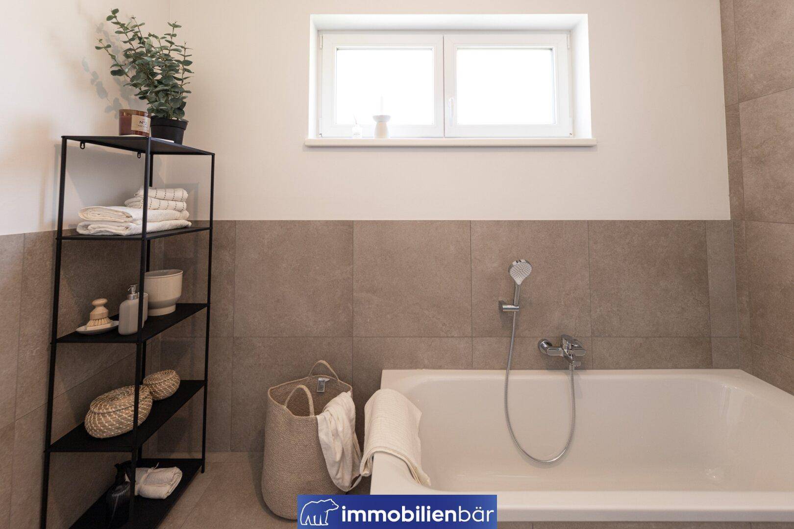 Modernes Badezimmer mit Badewanne, dunklem Regal und Fenster für natürliches Licht.