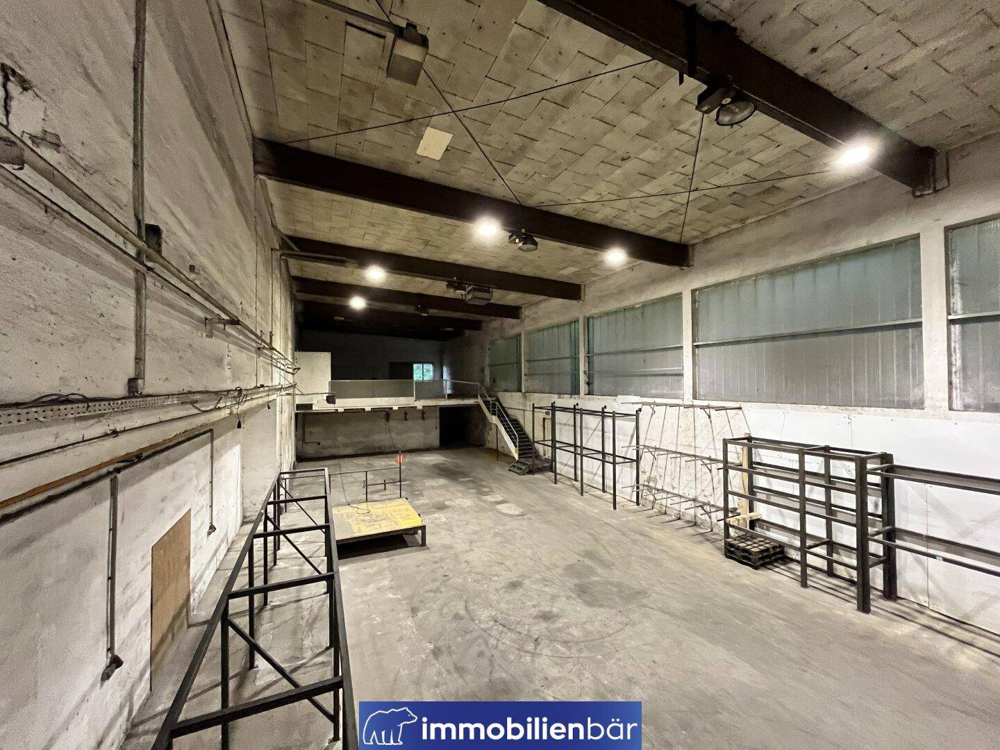Weitläufige Lagerhalle mit hohen Decken, Betonboden und Regalsystemen, bereit zur vielseitigen Nutzung.