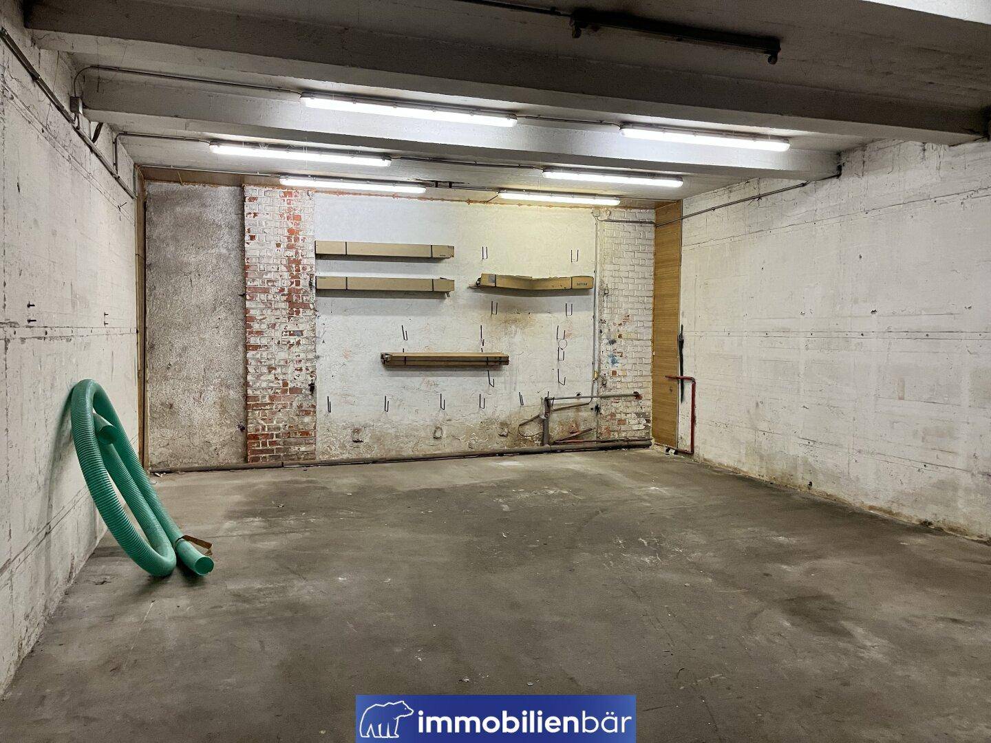 Kellerraum mit Betonboden, unverputzten Wänden und einfacher Beleuchtung, ideal als Lagerfläche.