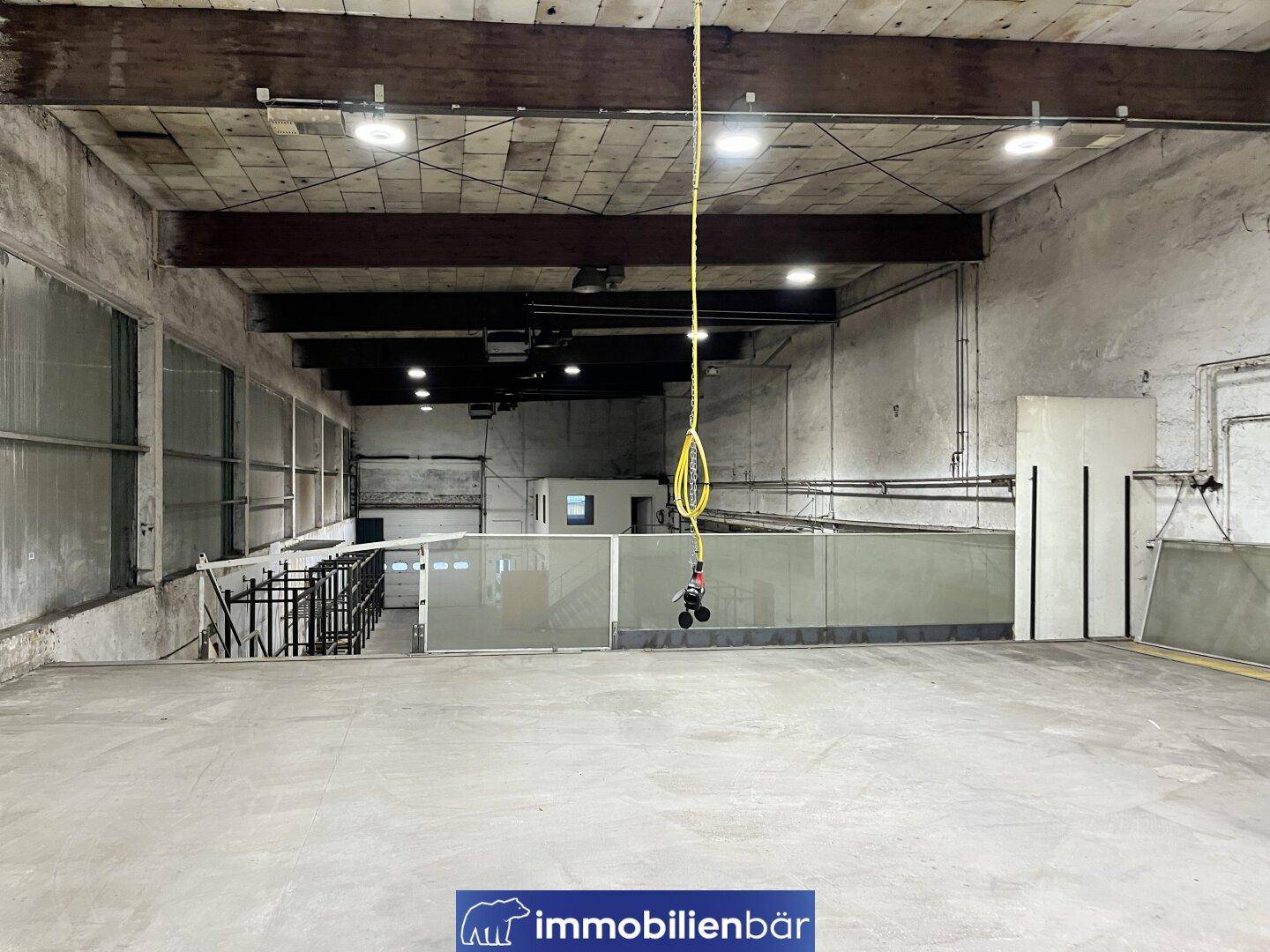 Weitläufige Lagerfläche mit Betonboden, hohen Decken und einer erhöhten Plattform im Vordergrund.