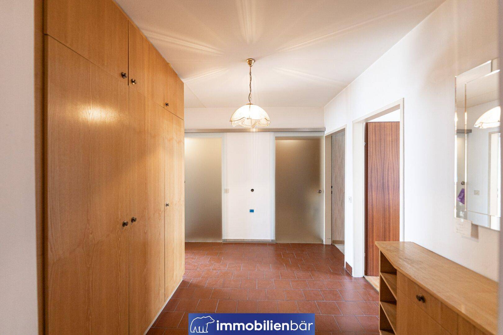 Geräumiger Flur mit Terrakotta-Fliesenboden und praktischen Einbauschränken.