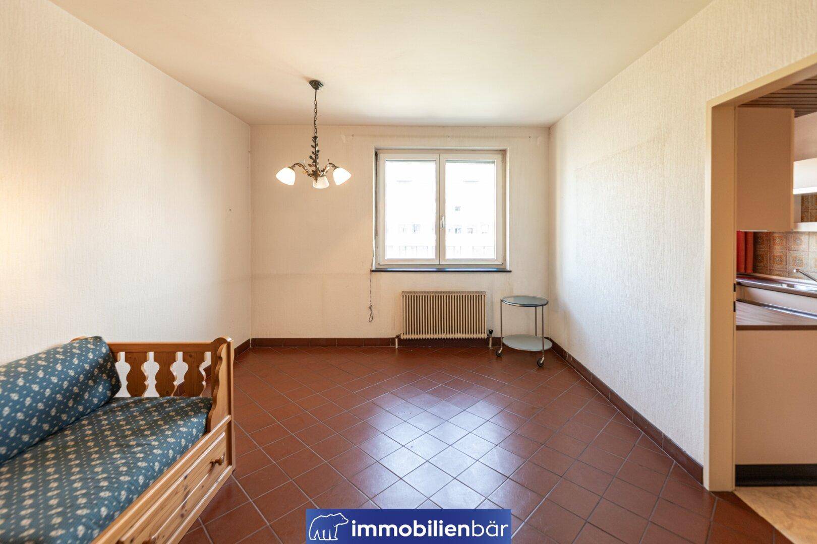 Esszimmer mit Terrakotta-Fliesenboden, großem Fenster und Tagesbett, angrenzend an die Küche.